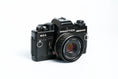 Load image into Gallery viewer, 'Praktica BCA + Prakticar 50mm f/2.4 + free 35mm film – Electronic vintage SLR'
